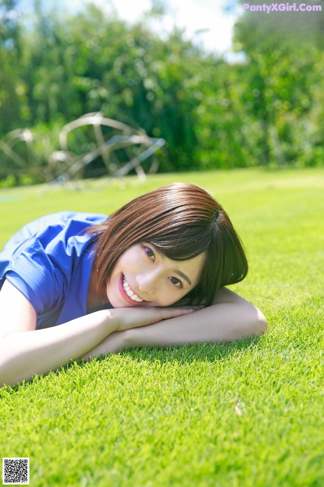 A woman laying on the grass in a blue shirt.