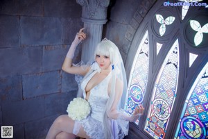 A woman in a wedding dress sitting on a chair.