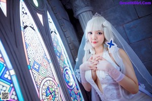 A woman in a wedding dress standing in front of a stained glass window.