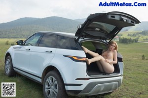 A woman in a white dress is sitting in a car.