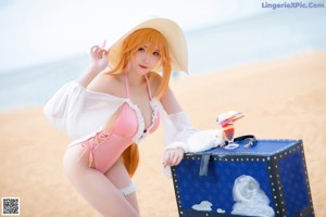 A woman in a pink bikini sitting on a beach.