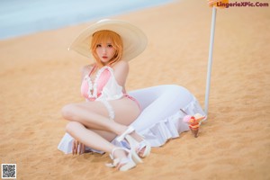 A woman in a pink bathing suit and hat on the beach.