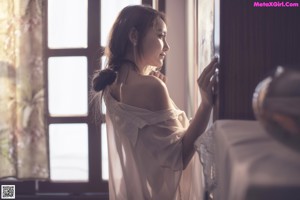 A woman sitting on a bed next to a lamp.