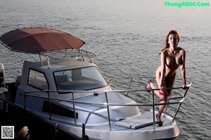 A woman in a red and blue bikini sitting on a boat.