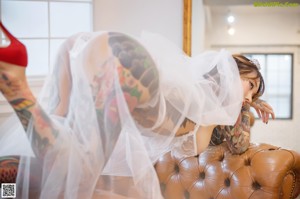 A woman with tattoos on her arms and chest wearing a wedding dress.