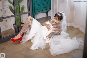 A woman with tattoos sitting on a brown leather chair.