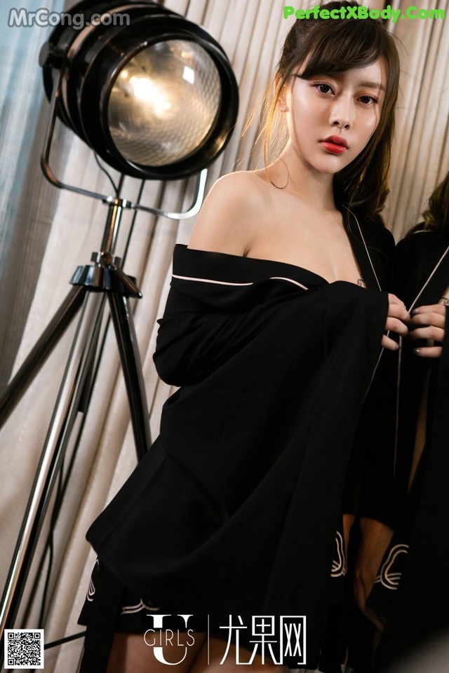 A woman in a black dress standing in front of a camera.