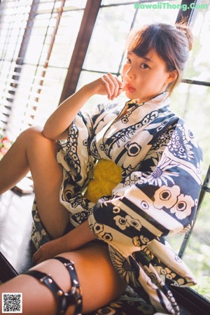 A woman sitting on a bed in a black and white dress.