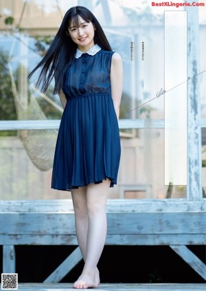 A woman in a blue dress standing on a wooden bridge.