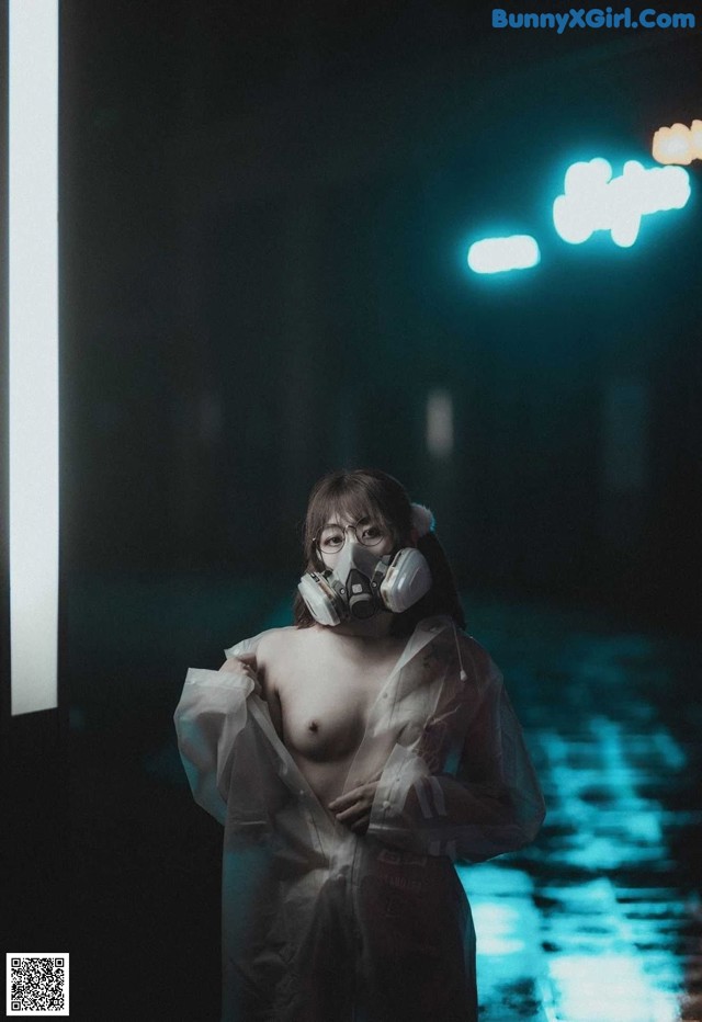 A woman wearing a gas mask standing in a dark room.