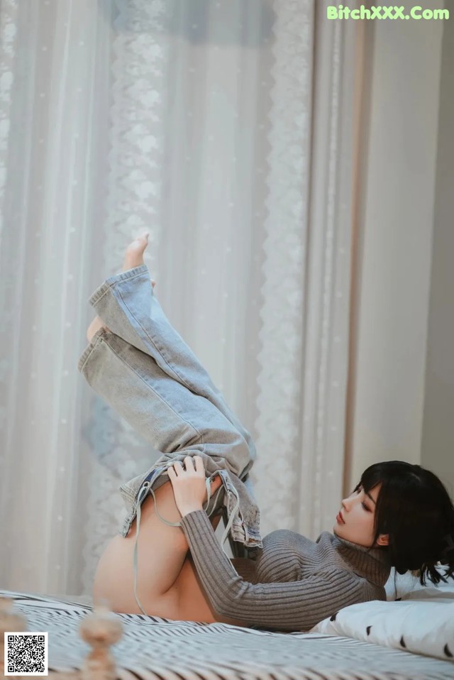 A woman laying on top of a bed with her legs up.